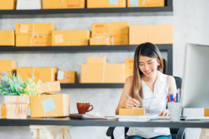 Photo: young Asian woman preparing to send packages with business shipping services